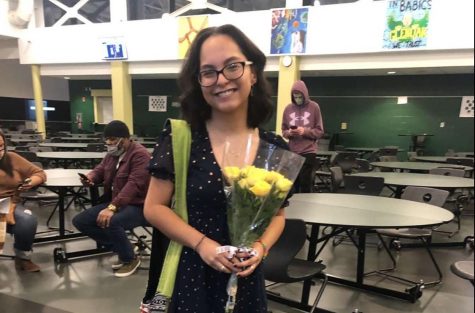 Image of Lizbeth Cisneros holding flowers at a community event. Lizbeth learned both Spanish and English at the same time .