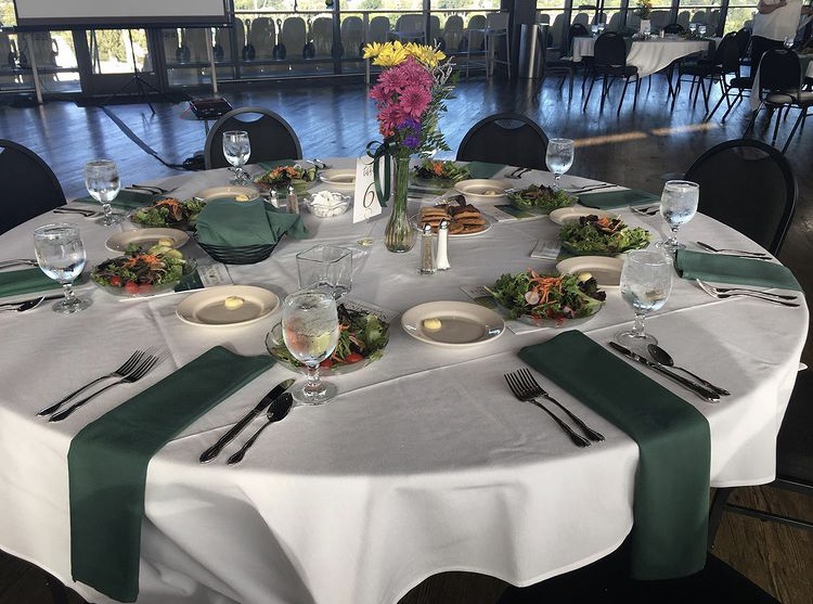 2021 Hall of Distinctions Ceremony table featuring a centerpiece made by horticulture students and entrees of salad and cookies.