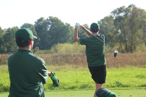 GlenOak golfer swings while teammate watches.