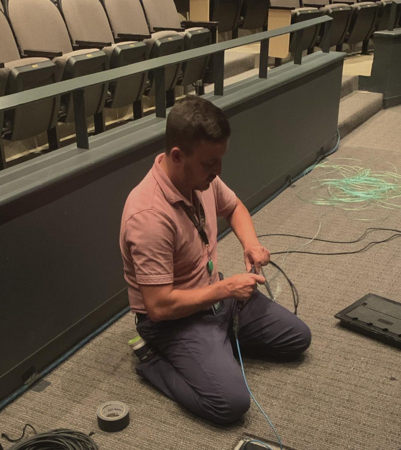 New Light & Sound teacher Anthony Depinto works on running a cable under the theater up to the booth. 