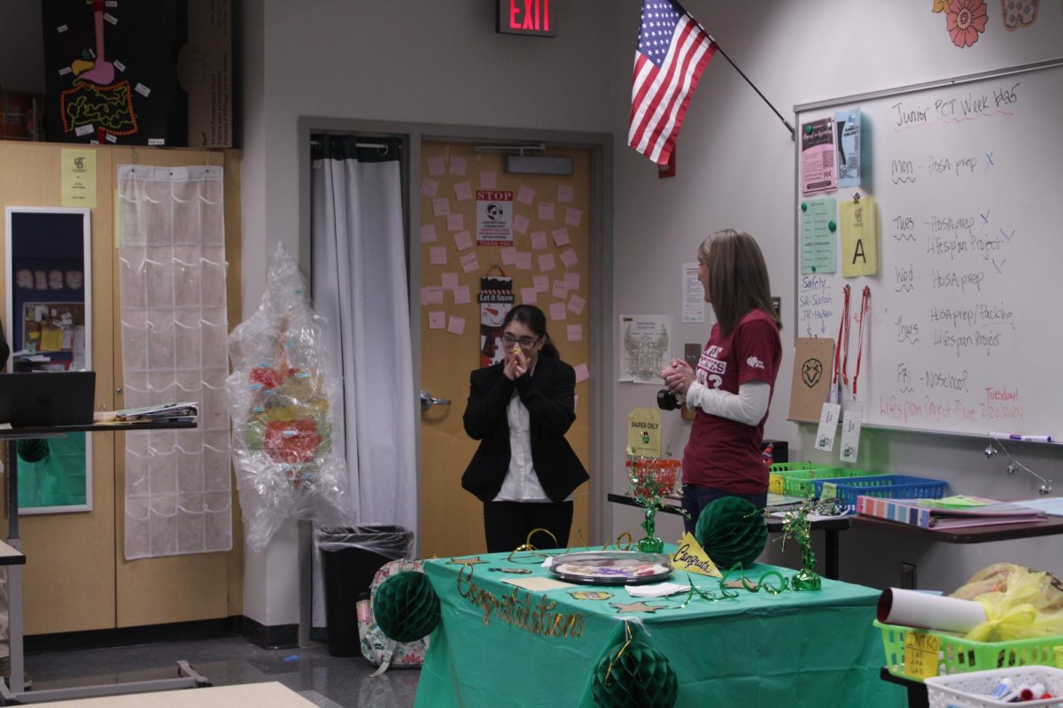Big Surprise: Senior Carolynn Armstrong and school consular Theresa Rhoads stand in front of the nursing class. We wanted it to be a surprise so we made sure to through her a little party before she could find out, Rhoads said.  Carolynn covers her mouth in happiness and shock.