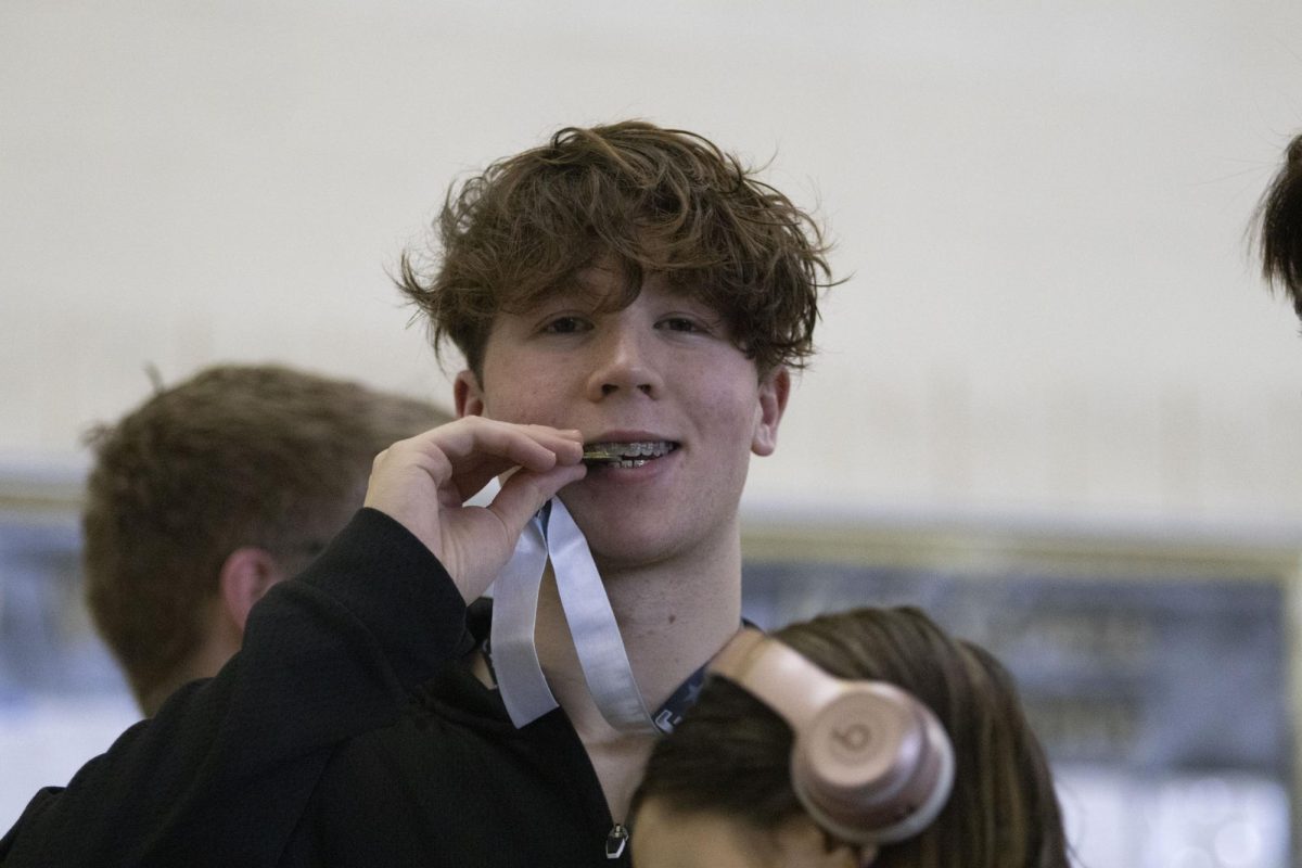 Noah Fitzsimmons biting medal at swim meet