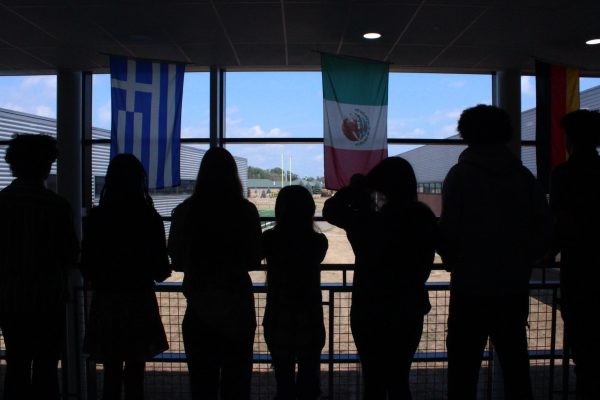 Unidentified students stand in the hall looking over the railing. 