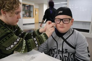 Senior Halle Speelman paints a student's face during Boo at the School. Speelman got five volunteer hours for participating in Boo at the School.