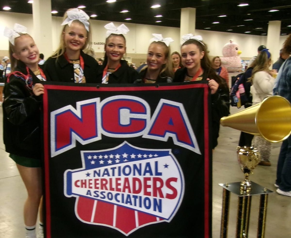 The cheerleading team poses with their National Champion banner.