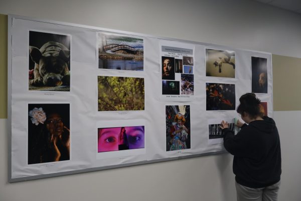 Commercial photography student Kiya Koons hangs pictures on the bulletin board in the main hallways. Photography will be having their artists reception on May 5, 6-8 p.m.